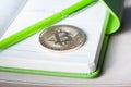 A single golden bitcoin on a green notepad