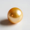 A single golden pearl resting on a smooth, light-colored surface with a subtle shadow Royalty Free Stock Photo