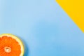 Single grapefruit slice closeup on blue and diagonal yellow back Royalty Free Stock Photo