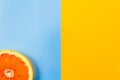 Single grapefruit slice closeup on blue and yellow background Royalty Free Stock Photo