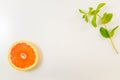 Single grapefruit slice and mint leaves on white background Royalty Free Stock Photo