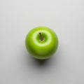 A single green apple, likely a Granny Smith, is centrally positioned on a light gray Royalty Free Stock Photo