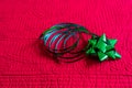 A single green present bow and looped ribbon on a red quilt Royalty Free Stock Photo