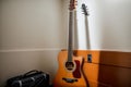 A single guitar leaning against a dorm room wall resonating with stories