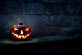 A single halloween Jack O Lantern on the left side of a dark blue night stone plinth Royalty Free Stock Photo