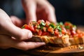 single hand grasping a piece of bruschetta