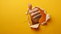 single hand protruding through a torn yellow paper background, making a thumbs-up gesture.. AI generated Royalty Free Stock Photo