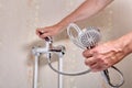 Plumber fixing leaky single handle shower faucet in bathroom.