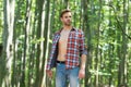 Single handsome guy with sexy bare torso in open shirt casual style stand in woods on sunny summer day natural landscape