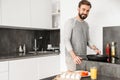 Single happy man wearing casual clothing cooking dinner on frying pan with eggs, and vegetables in modern apartment Royalty Free Stock Photo