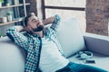 Single, happy young man in checkered shirt is relaxing on the so