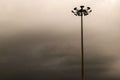 Single high lighting pole against a cloudy sky