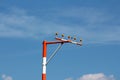 Single high metal red and white pole with multiple airport runway guiding lights on cloudy blue sky