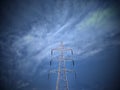 Single high-voltage post or tower isolated on cloudy blue sky background. Royalty Free Stock Photo