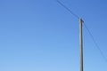 A single high voltage power line against blue cloudless sky. Overhead line on a wood pylon