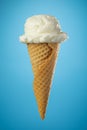 Single ice cream cone with vanilla icecream and a waffle cone on blue background Royalty Free Stock Photo