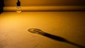 Single incandescent light bulb casting a long shadow on a textured yellow surface Royalty Free Stock Photo