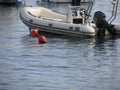 Single inflatable dinghy with outboard motor lies at anchor in a harbor . Tuscany, Italy Royalty Free Stock Photo