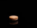 A single isolated pill or medicine tablet on black background