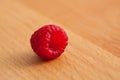 Single juicy raspberry on a wooden surface with copy space