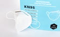 Single KN95 professional white protective medical face mask with filter beside a box, closeup, nobody. Simple new KN 95 anti viral