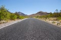 Single lane paved road in the desert at the foothills of the mountains