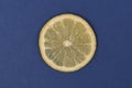 A single lemon slice on a blue background
