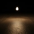 A single light bulb hangs from the ceiling, illuminating a dark room Royalty Free Stock Photo