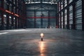 A single lightbulb shines brightly in the center of a vast, empty warehouse, symbolizing hope and innovation in a Royalty Free Stock Photo