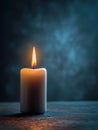 Single lit candle casting warm glowing light on textured surface with dark blurred background for peaceful ambiance and reflection Royalty Free Stock Photo