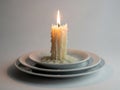 Single lit candle on stacked plates Royalty Free Stock Photo