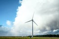 Single lone electric generating wind turbine windmill with dramatic big storm cloud and rainbow and nature park forest woodland Royalty Free Stock Photo