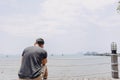 Single lonely man sitting alone looking out to the sea bay. Royalty Free Stock Photo