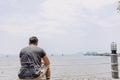 Single lonely man sitting alone looking out to the sea bay. Royalty Free Stock Photo