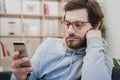 Single lonesome man checking mobile phone on the couch Royalty Free Stock Photo