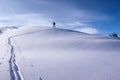 A single male back country skier skiing along a long snow ridge