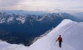 Single male mountain climber in red on a narrow snow ridge