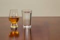 Single malt Scotch whisky and peated barley in a glen cairn glass on a rustic wooden table beside a traditional glass of water Royalty Free Stock Photo