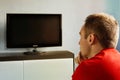 Single man on the couch watching tv, changing channels. The young guy watches the TV turned off carefully. Royalty Free Stock Photo