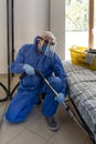 Single man in quarantine dressed in protective suit is cleaning house