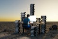 single man sitting at pc office workplace in desert environment with huge stacks of document binders workload stress burnout Royalty Free Stock Photo