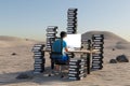 single man sitting at pc office workplace in desert environment with huge stacks of document binders workload stress burnout Royalty Free Stock Photo