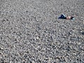 A single man sleeping in the sun on a grey pebble beach in Funchal, Madeira