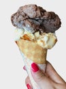 Single melting chocolate vanilla ice cream scoop flavor in waffle cone in hand holding on white Royalty Free Stock Photo