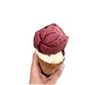 Single melting purple and vanilla ice cream scoop flavor in waffle cone in hand holding on white Royalty Free Stock Photo