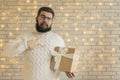 Single middle adult man with beard and mustache on face hold Christmas gift and posing in studio room with white brick wall Royalty Free Stock Photo