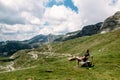 Single millenial man sits on a bench on a mountain plateau and looks at the mountains in front of him. Montenegro, Durmitor.