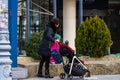 Single mom with child pushing baby stroller in Bucharest, Romania, 2022