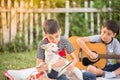 Single mom and sons play guitar together in the park