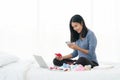 Single mom start working day on a laptop sitting on the bed in the morning. Working from home concept, shopping online